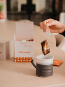 A Coffeeangel brew bag being lowered into a stoneware mug