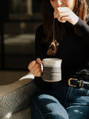 Traditional stoneware mug held while drinking coffee