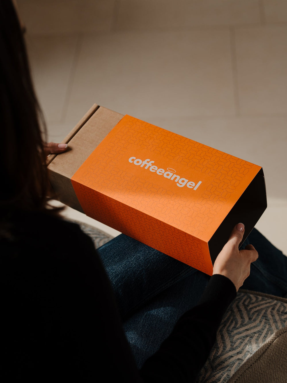 The Coffeeangel gift box in its orange sleeve, being handed to someone