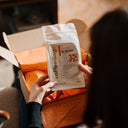 An open Coffeeangel coffee gift box with two coffee bags nestled in orange tissue